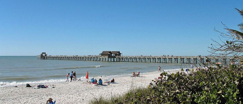 Naples Pier stretching into the Gulf of Mexico from a white sand beach